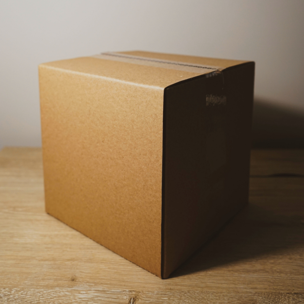 Photo of a closed cardboard box sitting on a wooden surface.